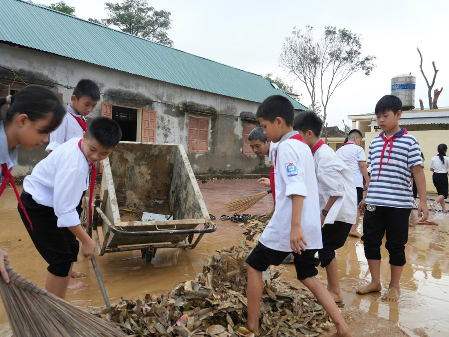Học sinh Trường THCS Kỳ Tân, xã Tân Kỳ, Nghệ An tham gia dọn dẹp, vệ sinh sân trường sau lũ. Ảnh: Hồ Lài